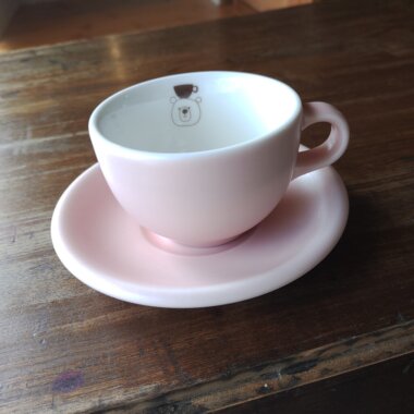 頭の上にコーヒーカップをのせたくまがデザインされたピンクのコーヒーカップとソーサー
