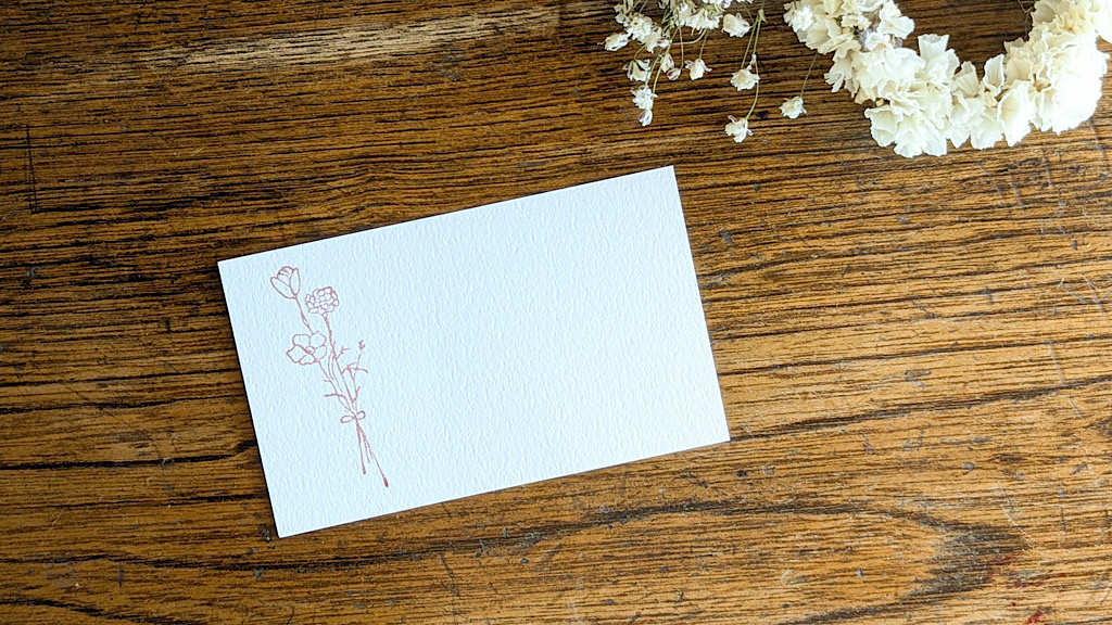 赤い花のスタンプが押された白いメッセージカード